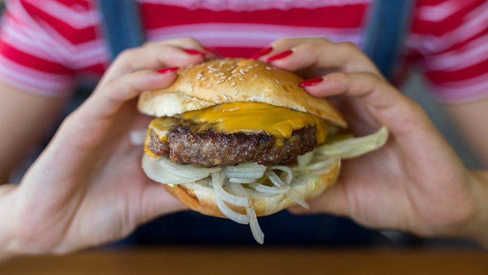 Woman eating a cheeseburger.